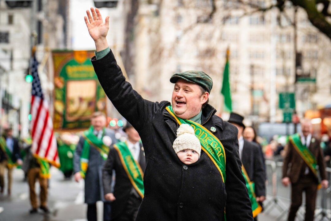 A man carries a baby during the Saint Patrick's Day Parade in New York City on March 17, 2025. (Samira Bouaou/The Epoch Times)
