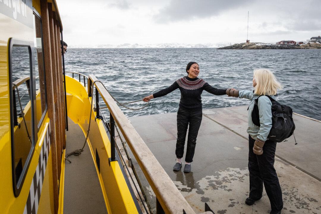 Pakkutannguaq Larsen helps tourists exit a boat in Nuuk, Greenland, on May 4, 2025. (John Fredricks/The Epoch Times)