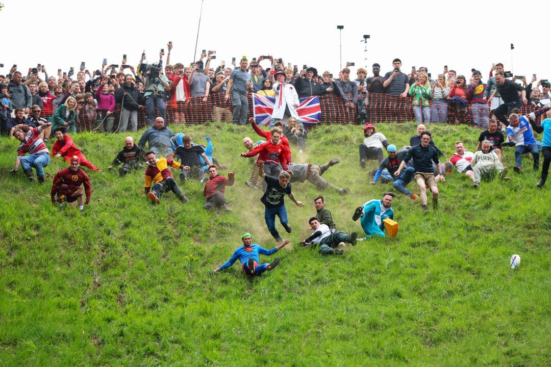 Contestants in the Men's Downhill Race chase a wheel of cheese down a hill in Brockworth, England, on May 26, 2025. Every year, competitors and spectators from around the world gather for the Cooper's Hill Cheese-Rolling competition that sees participants fling themselves down a steep hill in pursuit of a rolling 7-pound wheel of Double Gloucester cheese. The first contestant to the bottom of the 590-foot Cooper's Hill wins the wheel of cheese. The ankle-breaking extreme sport has officially been recorded since 1826 but is thought to have roots in an ancient pagan tradition. (Cameron Smith/Getty Images)