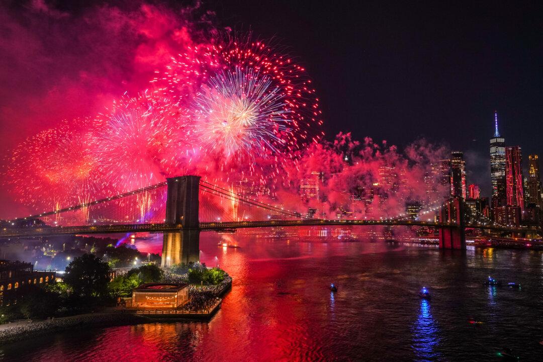 People watch as fireworks light up the sky above the Brooklyn Bridge during Macy's Fourth of July fireworks show in New York City on July 4, 2025. More than 80,000 shells lit up the sky in this year's 25-minute show, the 49th edition, with fireworks launched from four barges and the Brooklyn Bridge. (Adam Gray/Getty Images)