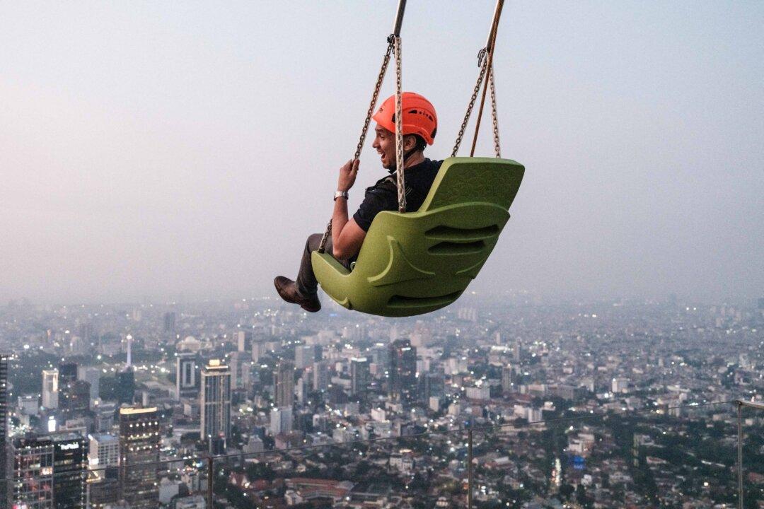 A man rides a swing at the edge of an observatory deck claimed to be Indonesia's highest at the Thamrin Nine building in Jakarta, Indonesia, on July 24, 2025. (Yasuyoshi Chiba/AFP via Getty Images)