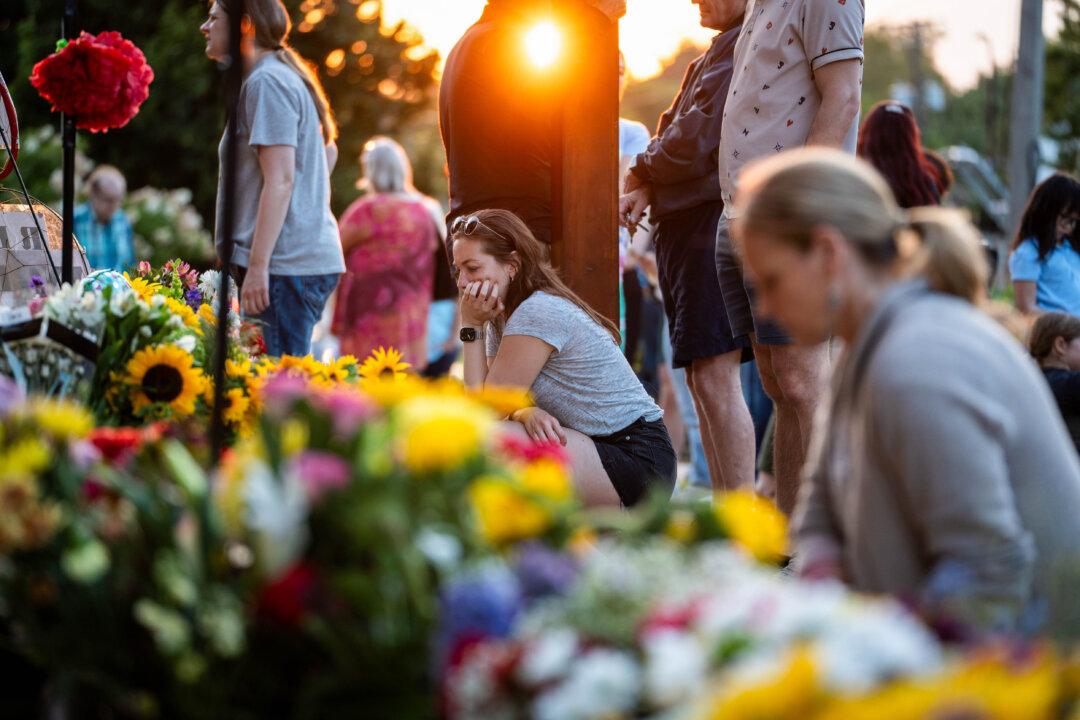 At a makeshift memorial, people mourn two schoolchildren who were killed a day before during the Annunciation Catholic School shooting, in Minneapolis on Aug. 28, 2025. A gunman fired through the stained-glass windows of the church during a Catholic school Mass, killing two children and injuring more than 20 others. (Madalina Kilroy/The Epoch Times)