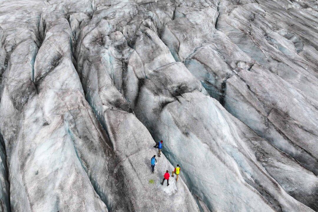 An aerial view of a scientific team from the Swiss Federal Institute of Technology in Zurich standing among crevasses on the Rhone Glacier during data collection near Gletsch, Switzerland, on Aug. 22, 2025. The scientific team of researchers and students measured a variety of the glacier's properties, including its mass loss and surface reflectivity, ice flow, ice thickness, hydrological characteristics, and the size and deformation of crevasses. (Sean Gallup/Getty Images)