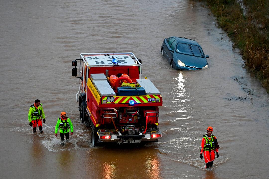 French rescue workers walk past a car along the Herault river, which overflowed following heavy rains in Agde, France, on Dec. 23, 2025. The Herault district in southern France remains under red alert for exceptional flooding, according to France's weather agency Meteo-France. (Sylvain Thomas/AFP via Getty Images)