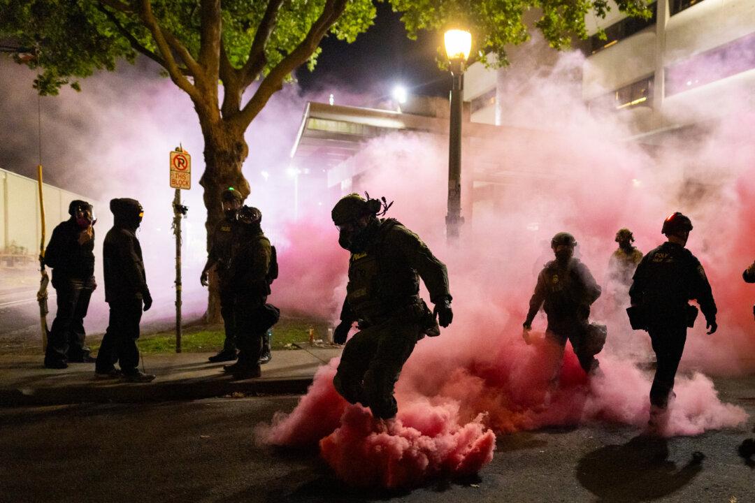 Federal officers deploy smoke grenades to deter protesters in front of Immigration and Customs Enforcement offices in Portland, Ore., on Oct. 5, 2025. Protests have erupted daily after the Trump administration announced a plan to send National Guard troops into Portland. (John Fredricks/The Epoch Times)