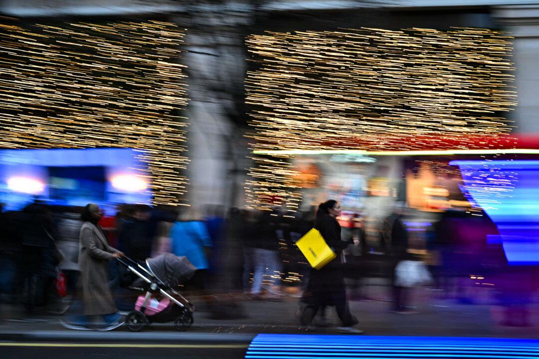 Last-minute shoppers pass seasonal store windows along Oxford Street in central London on Dec. 23, 2025. (Ben Stansall/AFP via Getty Images)