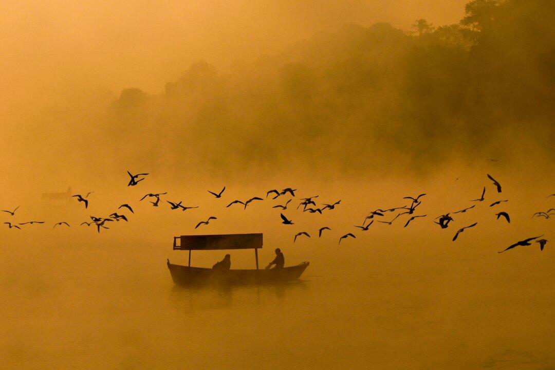 Men row a boat amid dense fog across the Narmada River in Jabalpur, India, on Nov. 11, 2025. (Uma Shankar Mishra/AFP via Getty Images)