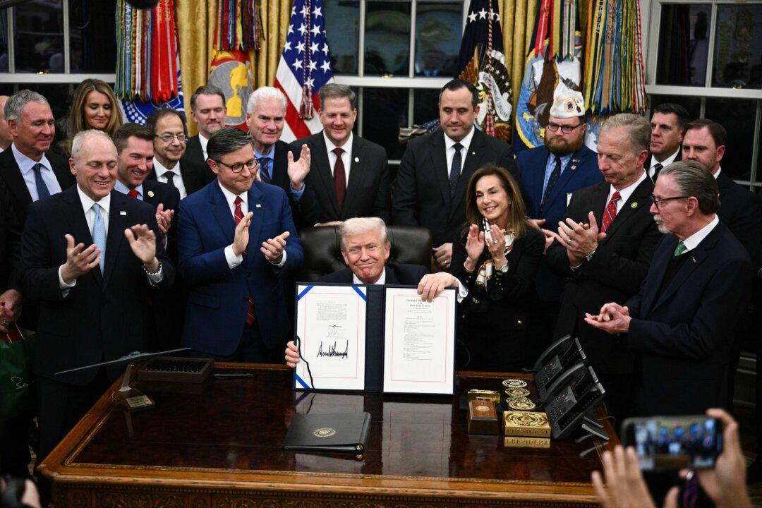 President Donald Trump shows the signed bill package to reopen the federal government, in the Oval Office on Nov. 12, 2025. The 43-day shutdown was the longest in U.S. history. (Brendan Smialowski/AFP via Getty Images)