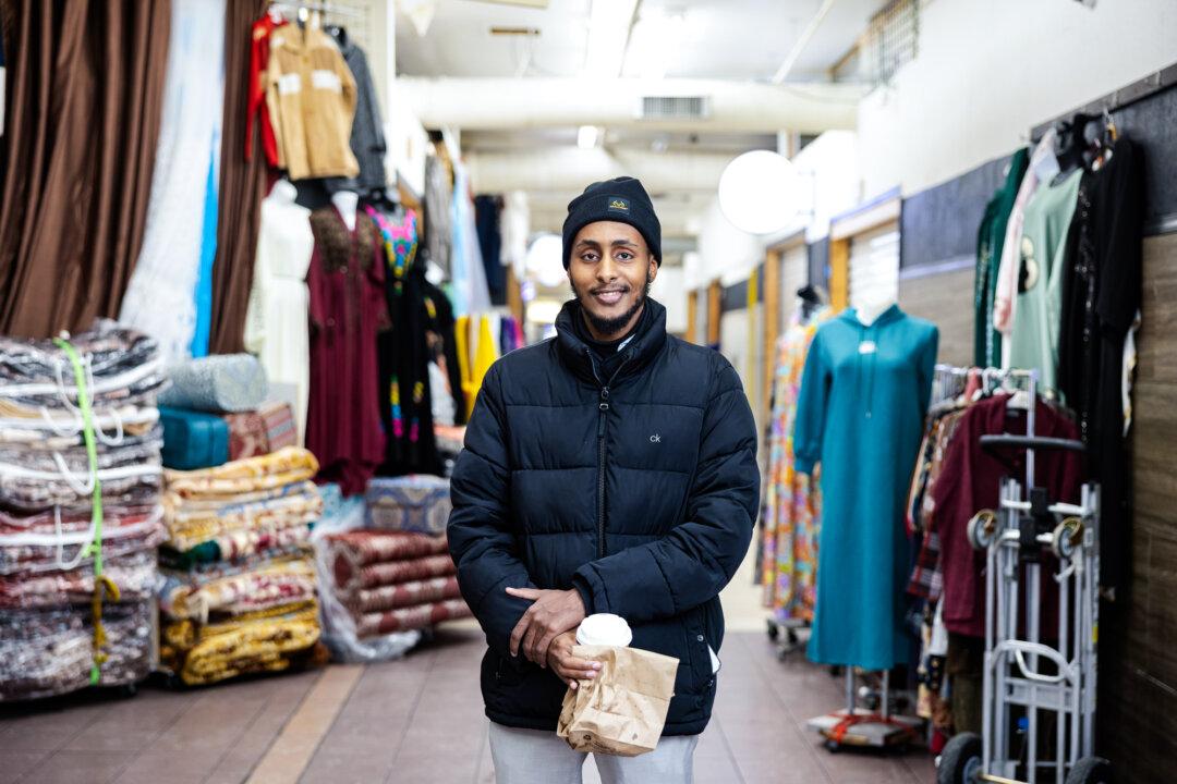 A portrait of Shuaib Omar at Karmel Mall in Minneapolis on Dec. 9, 2025. Omar, a young Somali man, described a sense of fear and uncertainty gripping his community because of immigration enforcement and the labeling of their group as fraudsters. (Jenn Ackerman for The Epoch Times)
