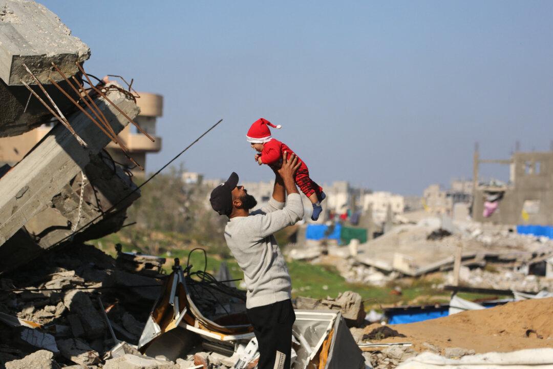 A man lifts a child next to the rubble of destroyed buildings in the Jabalia refugee camp, in the northern Gaza Strip on Dec. 24, 2025. (Bashar Taleb/AFP via Getty Images)