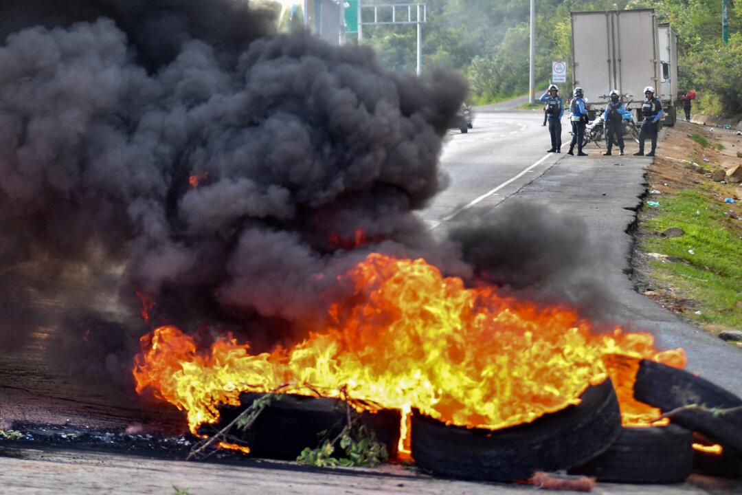 Honduran National Police members get ready to remove burning tires set by supporters of the ruling Libertad y Refundacion party to block the road connecting Tegucigalpa with northern Honduras, in Tegucigalpa, Honduras, on Dec. 24, 2025. The protest takes place as the National Electoral Council prepares to announce the winner of last month's presidential election, which current tallies show is being led by conservative Nasry Asfura of the opposition National Party, supported by U.S. President Donald Trump. (Orlando Sierra/AFP via Getty Images)