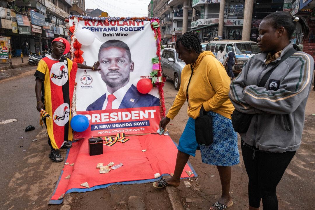 A woman donates money to a National Unity Platform presidential candidate Bobi Wine supporter in Kampala, Uganda, on Dec. 24, 2025. (Badru Katumba/AFP via Getty Images)