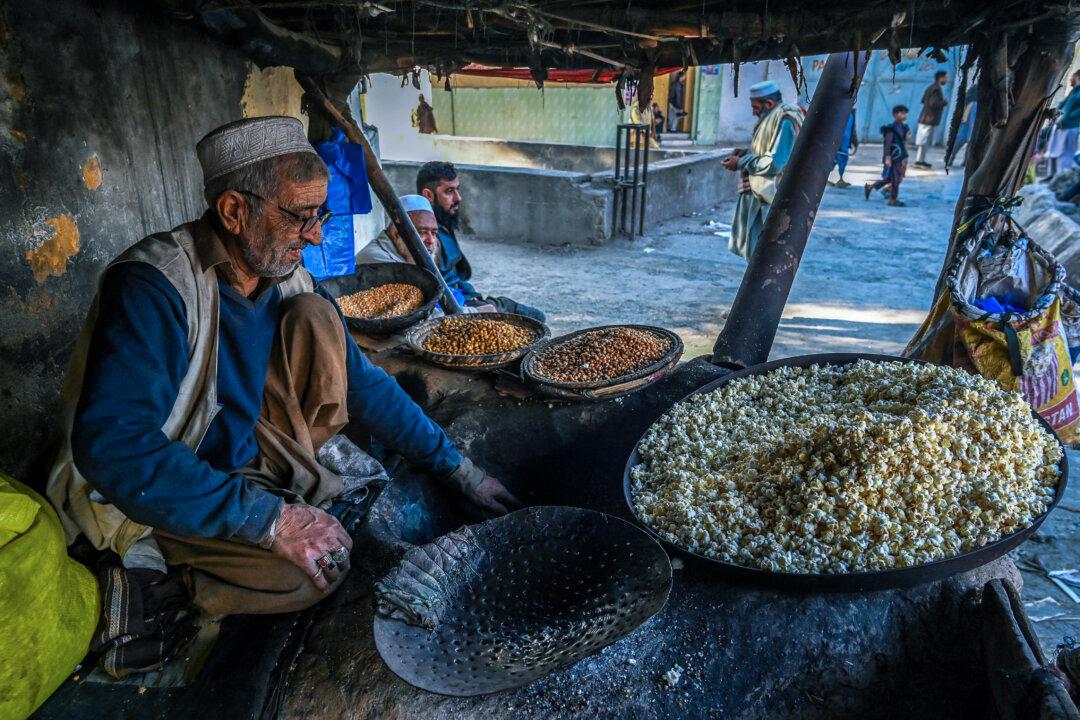 A vendor roasts kernels and popcorn at an old roadside shop under a makeshift shelter in Peshawar, Pakistan, on Dec. 25, 2025. (Abdul Majeed/AFP via Getty Images)
