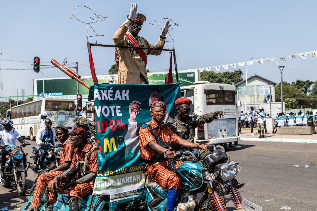 A supporter dressed as Guinea President and presidential candidate Mamady Doumbouya greets people as he is escorted by supporters pretending to be soldiers during the last day of campaign in Conakry, Guinea, on Dec. 25, 2025, ahead of Guinea's presidential election on Dec. 28, 2025. (Patrick Meinhardt/AFP via Getty Images)