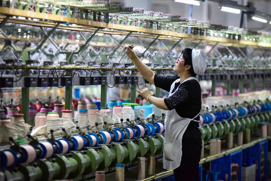 A worker checks a machine at a factory producing silk cloth in Fuyang, Anhui Province, China, on April 16, 2025. Economist Davy J. Wong said the deeper issue in China’s tariff evasion involves Chinese intermediate goods used in production in a third country—inputs he described as “legal, structural, and harder to police.” (STR/AFP via Getty Images)