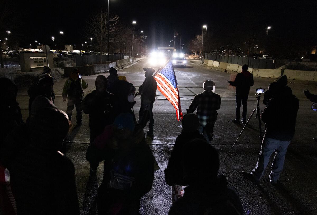 Protestors taunt federal officers with flags and microphones in front of the Bishop Henry Whipple Federal Building in Minneapolis on Jan. 11, 2026. (John Fredricks/The Epoch Times)