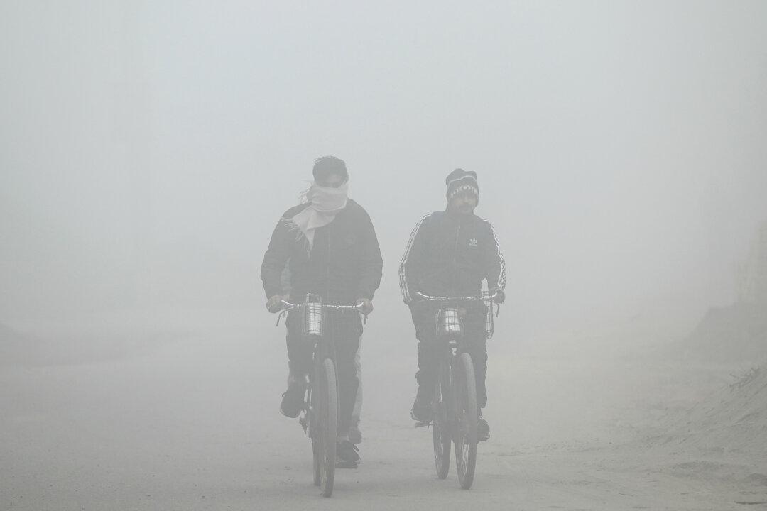 Laborers ride their bicycles in dense fog on the outskirts of Amritsar, India, on Jan. 12, 2026. (Narinder Nanu/AFP via Getty Images)