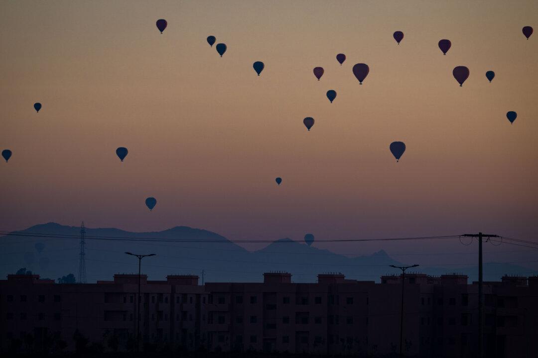 Hot air balloons lift off over buildings at sunrise near Marrakech, Morocco, on Jan. 12, 2026. (Sebastien Bozon/AFP via Getty Images)