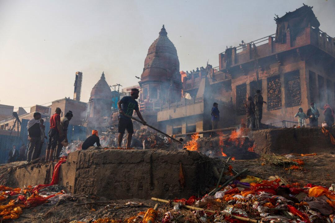 A cremator in the Dom community tends to a burning funeral pyre at the Manikarnika Ghat on the banks of the Ganges River in Varanasi, India, on Jan. 12, 2026. (Niharika Kulkarni/AFP via Getty Images)