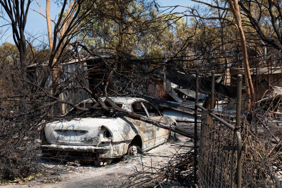 A burnt car lies crushed under a fallen tree in Harcourt, Australia, on Jan. 12, 2026. Bushfires have burned tens of thousands of acres in central Victoria, destroying multiple homes and other structures and forcing widespread evacuations under catastrophic fire conditions. (Jesse Thompson/Getty Images)