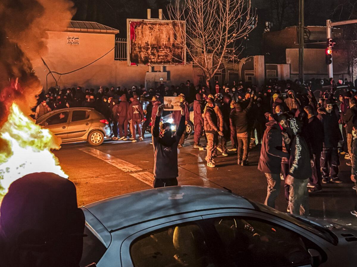 Iranians block a street in Tehran on Jan. 9, 2026, during ongoing nationwide mass protests. The man in the foreground is holding up a photo of Reza Pahlavi. (East Images/AFP via Getty Images)