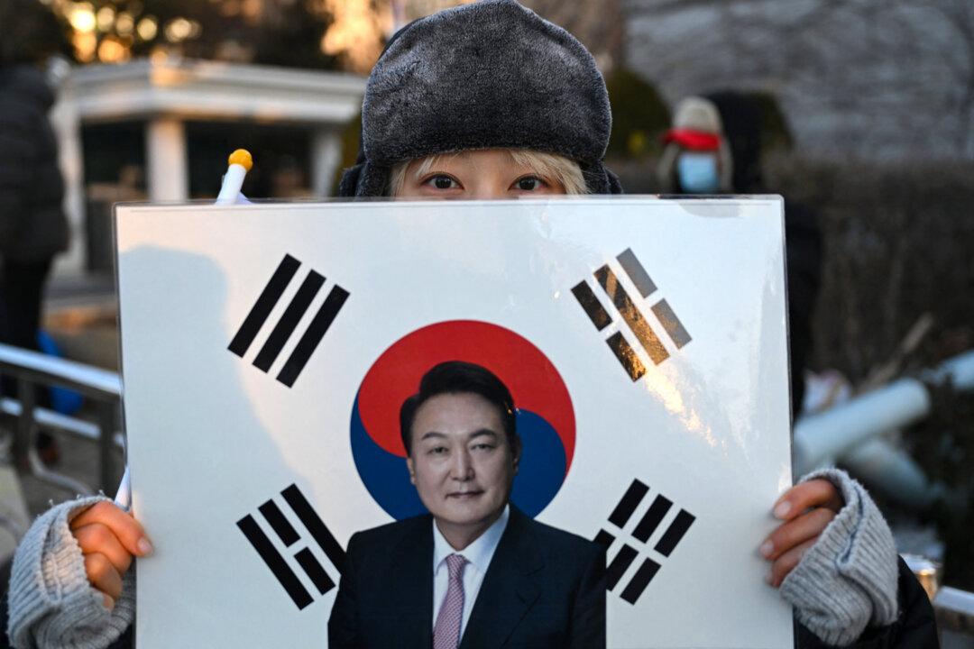 A supporter of South Korea's impeached former president Yoon Suk Yeol holds a placard showing a picture of Yoon in front of the Seoul Central District Court in Seoul, South Korea, on Jan. 13, 2026. Yoon's final criminal trial on insurrection charges is scheduled to be held in the court. (Jung Yeon-je/AFP via Getty Images)