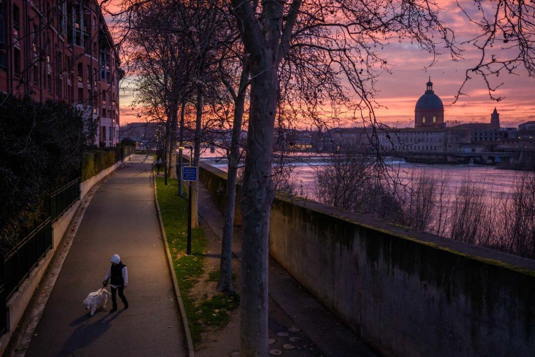 A woman walks a dog before sunrise near the Garonne river in Toulouse, France, on Jan. 13, 2025. (Ed Jones/AFP via Getty Images)