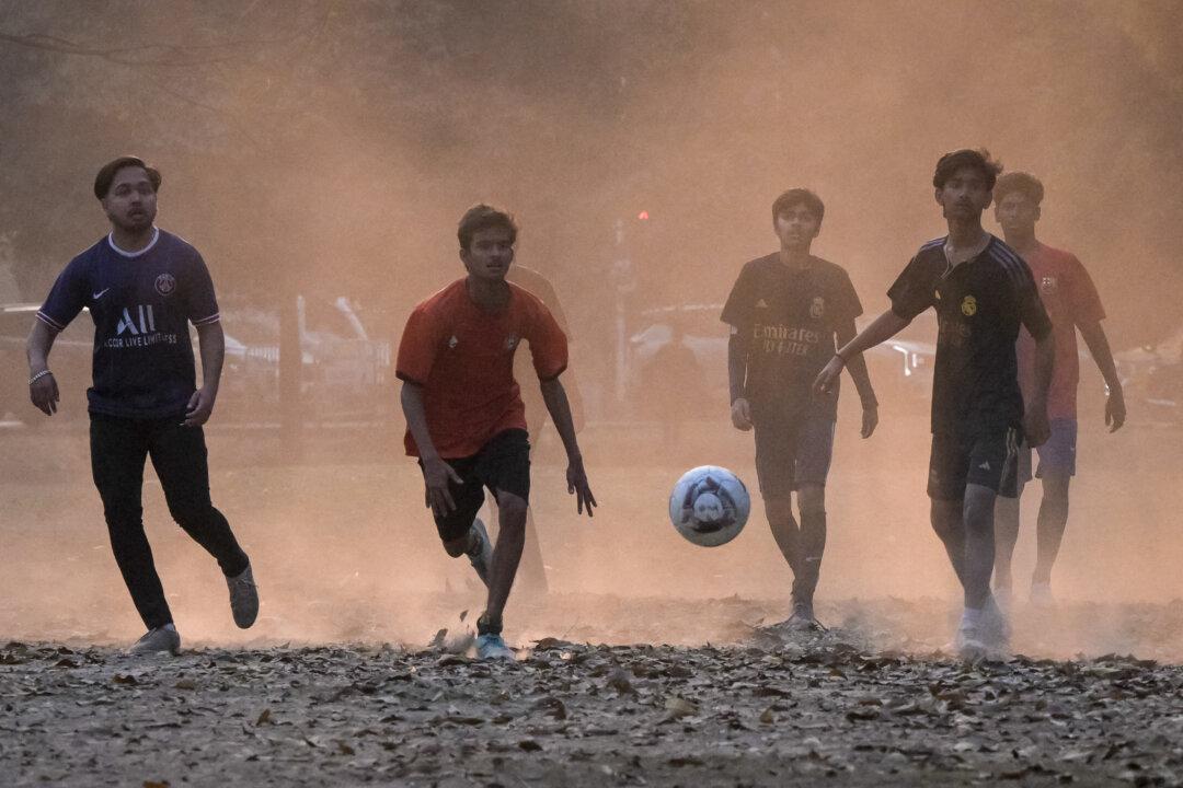 Boys play football on a dusty winter afternoon in Kolkata, India, on Jan. 13, 2026. (Dibyangshu Sarkar/AFP via Getty Images)