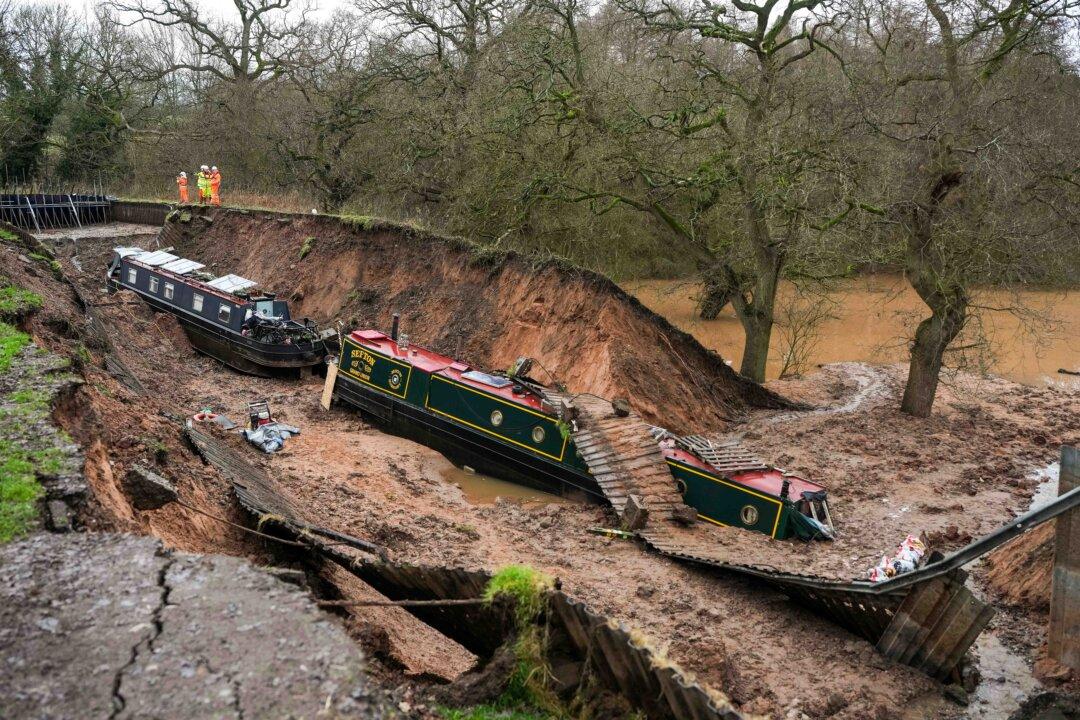 Stranded canal boats wait to be lifted from the bed of the Llangollen Canal after a breach in the embankment in Whitchurch, Shropshire, UK, on Jan. 13, 2026. A section of the canal collapsed on Dec. 22, plunging two narrowboats into a hole on the canal bed and leaving one teetering on the edge, with half a dozen others left stranded. (Christopher Furlong/Getty Images)