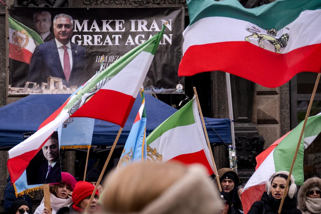 Protesters hold placards featuring Reza Pahlavi, an Iranian dissident in exile in the United States and son of Iran’s last shah, and wave Pahlavi-era flags during a demonstration against the Iranian regime at Stephansplatz in Vienna, Austria, on Jan. 11, 2026. (Joe Klamar/AFP via Getty Images)