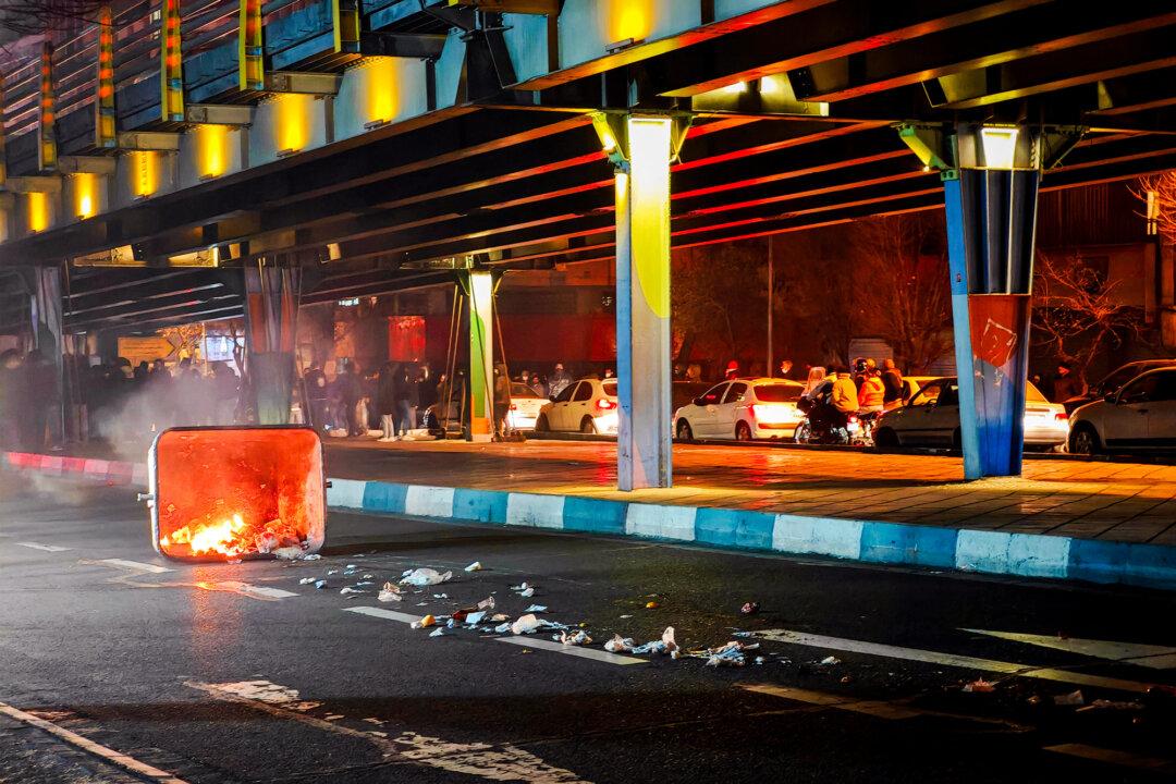 (Top Left) Iranians block a street, and vehicles are set on fire during a protest in Tehran, Iran, on Jan. 8–9, 2026. (Top Center) A vehicle burns during protests in Tehran, Iran, on Jan. 8, 2026. (Top Right) Iranians gather while blocking a street during a protest in Tehran, Iran, on Jan. 9, 2026. (Bottom Left) People gather during a protest in Tehran, Iran, on Jan. 8, 2026. (Bottom Center) People gather during a protest in Tehran, Iran, on Jan. 8, 2026. (Bottom Right) A dumpster burns during unrest in Tehran, Iran, on Jan. 8, 2026. (MAHSA/Middle East Images/AFP via Getty Images, Khoshiran/Middle East Images/AFP via Getty Images, Anonymous/Getty Images)