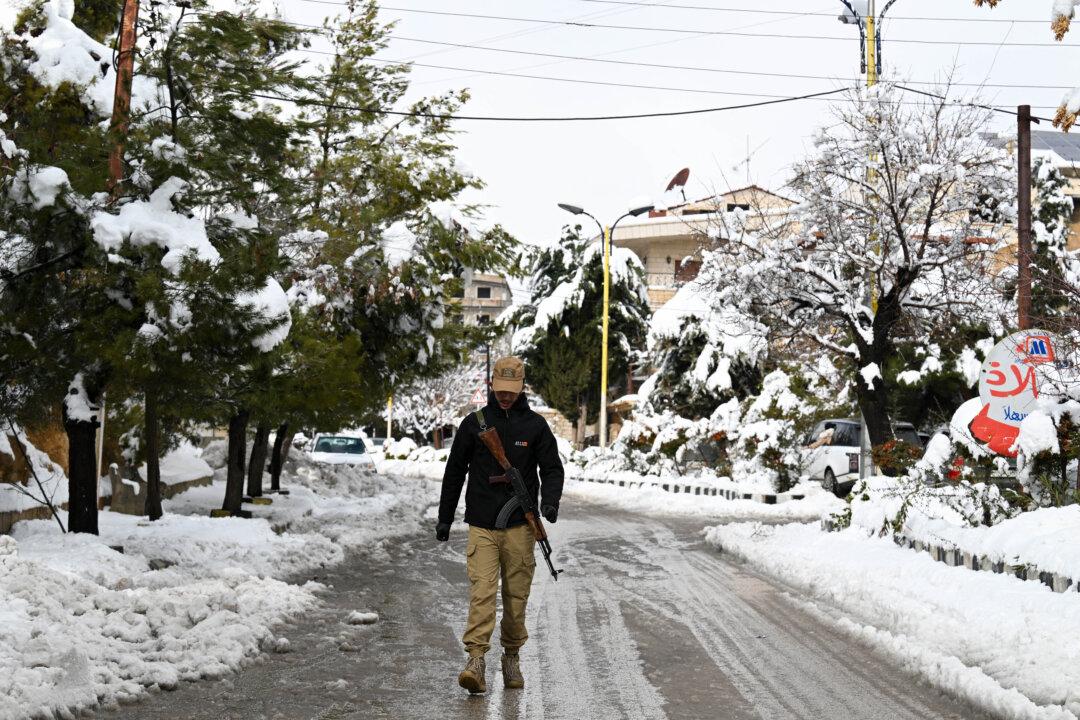 An armed man walks in the snow-covered Syrian town of Bloudan, some 50 kilometers northwest of the capital Damascus, on Jan. 14, 2026. (Louai Beshara/AFP via Getty Images)