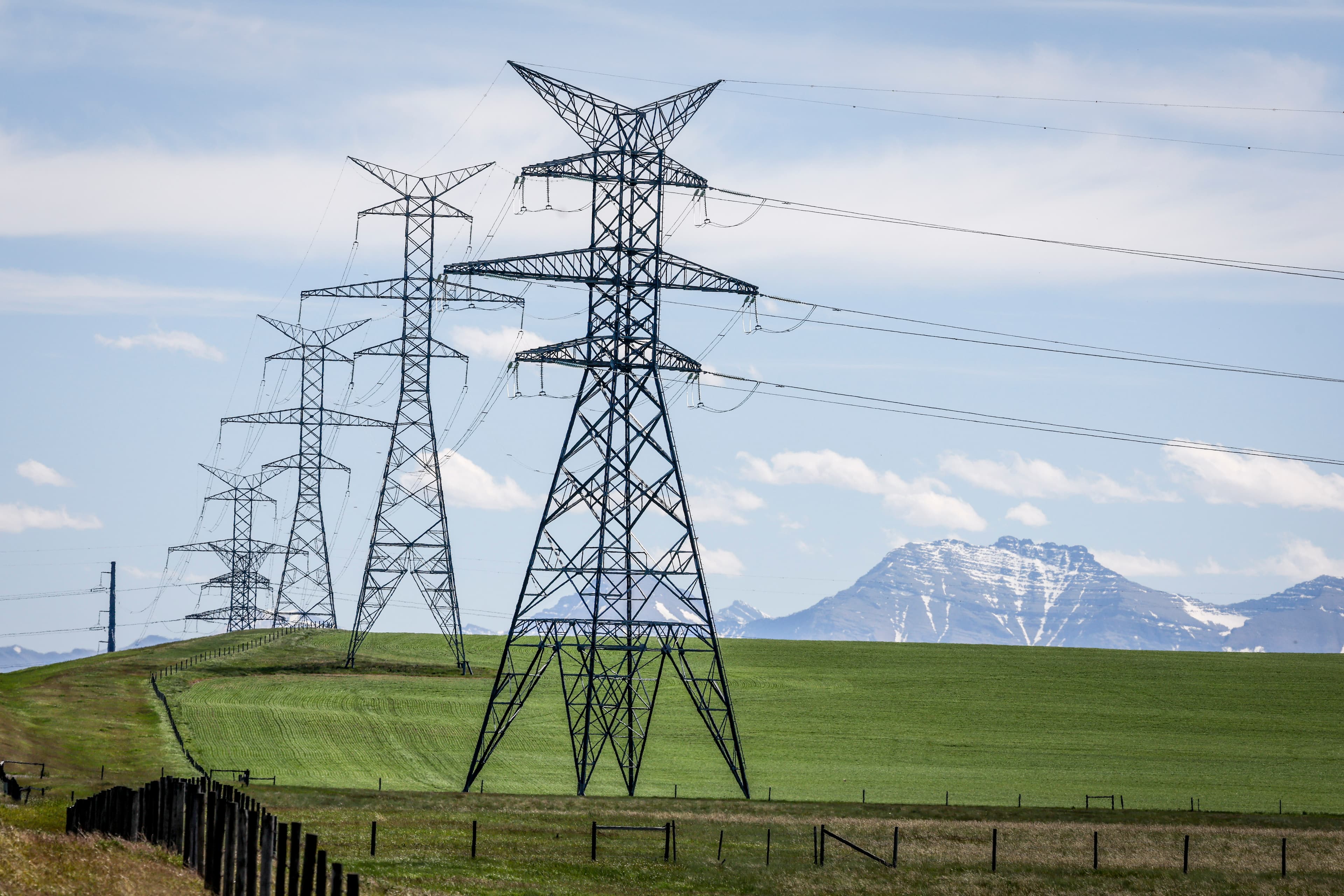 Power transmission lines are seen with the Rocky Mountains in the background near Pincher Creek, Alberta. Canada, on June 6, 2024. (The Canadian Press/Jeff McIntosh)