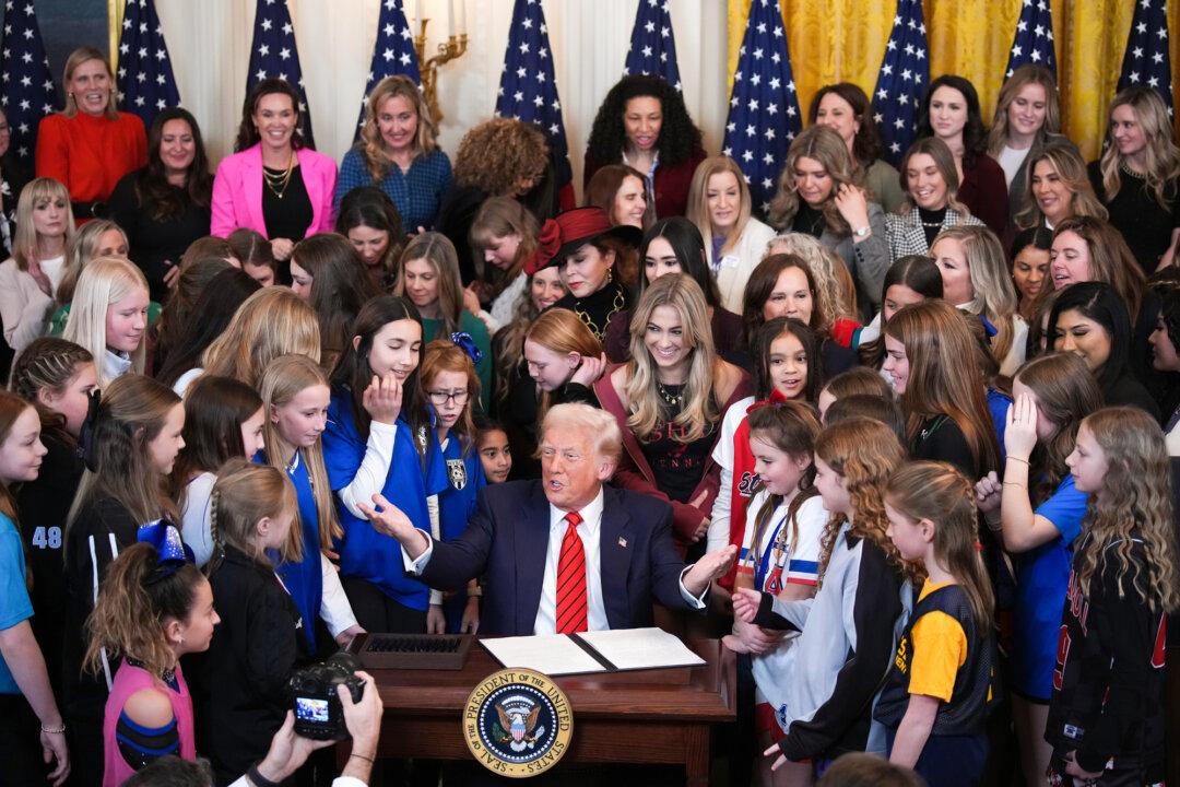 President Donald Trump, joined by women athletes, signs the “No Men in Women’s Sports” executive order in the East Room at the White House on Feb. 5, 2025. The executive order, which Trump signed on National Girls and Women in Sports Day, prohibits males who identify as transgender women from competing in women’s sports. (Andrew Harnik/Getty Images)