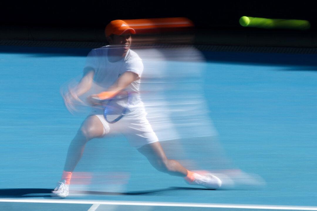 A slow shutter speed exposure captures the USA's Learner Tien as he hits a return to Kazakhstan's Alexander Shevchenko during their men's singles match on day four of the Australian Open tennis tournament in Melbourne, Australia, on Jan. 21, 2026. (Martin Keep/AFP via Getty Images)