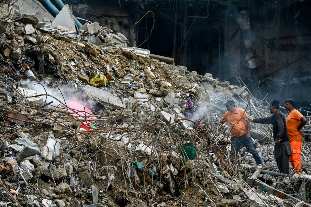 A shopkeeper (2nd R) points out his shop in the rubble after a deadly fire broke out at a shopping mall in Karachi, Pakistan, on Jan. 21, 2026. (Rizwan Tabassum/AFP via Getty Images)