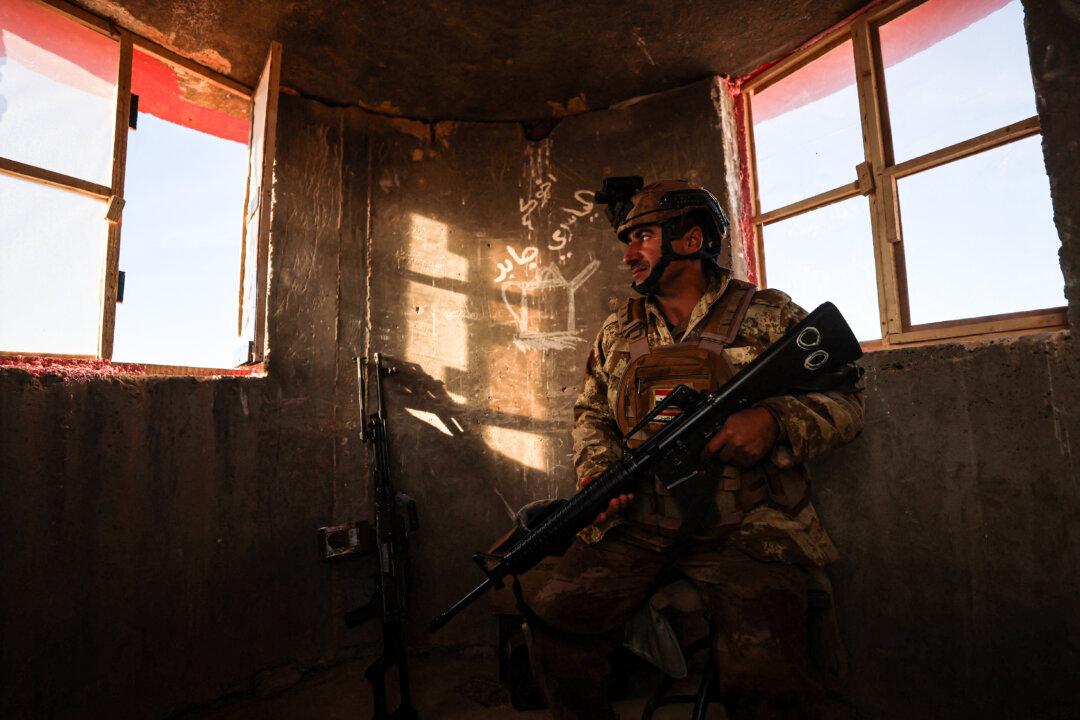 A member of the Iraqi border forces surveys the area from a watch tower along a concrete wall at the Iraqi–Syrian border, in the town of al-Baghuz in the Al-Qaim district of western Iraq, on Jan. 21, 2026, following recent events in neighboring Syria. (Ahmad Al-Rubaye/AFP via Getty Images)