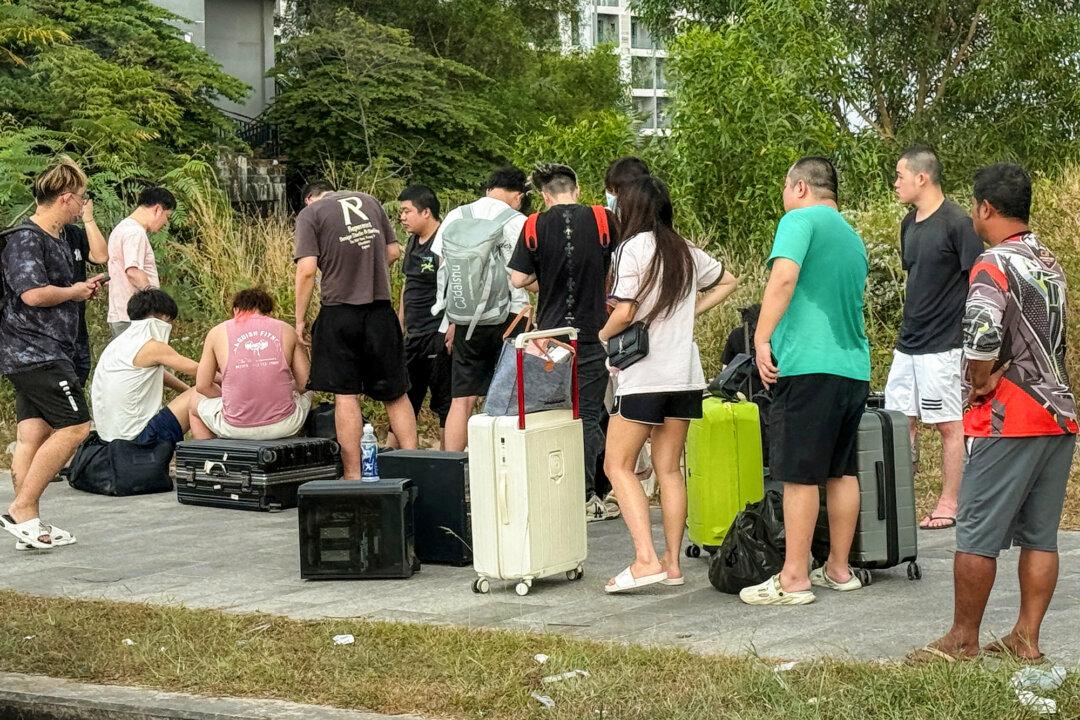 Workers gather with their luggage after leaving a suspected scam center compound in Sihanoukville, Cambodia, on Jan. 15, 2026. Hundreds of people fled the suspected Cambodian cyberfraud center after the arrest of alleged scam kingpin Chen Zhi. (Tang Chhin Sothy/AFP via Getty Images)
