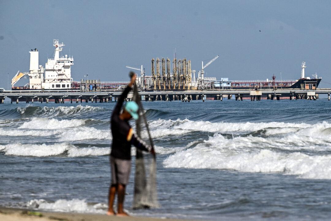 A fisherman stands by the sea as a tanker docks at the El Palito refinery pier, in Puerto Cabello, Carabobo state, Venezuela, on Jan. 22, 2026. (Ronaldo Schemidt/AFP via Getty Images)