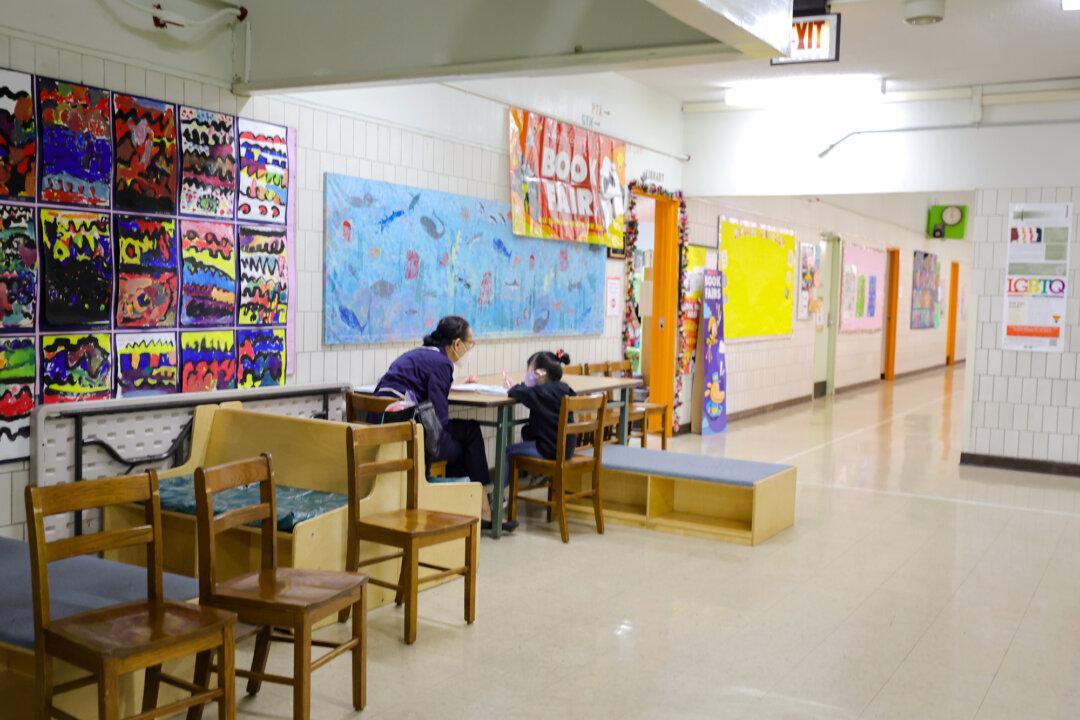 A pre-K student sits with a teacher outside a classroom at Yung Wing School P.S. 124 in New York on March 7, 2022. The Edunomics Lab found that of the roughly 200,000 positions added between the 2019–2020 and 2023–2024 school years, only 17 percent were teachers. (Michael Loccisano/Getty Images)