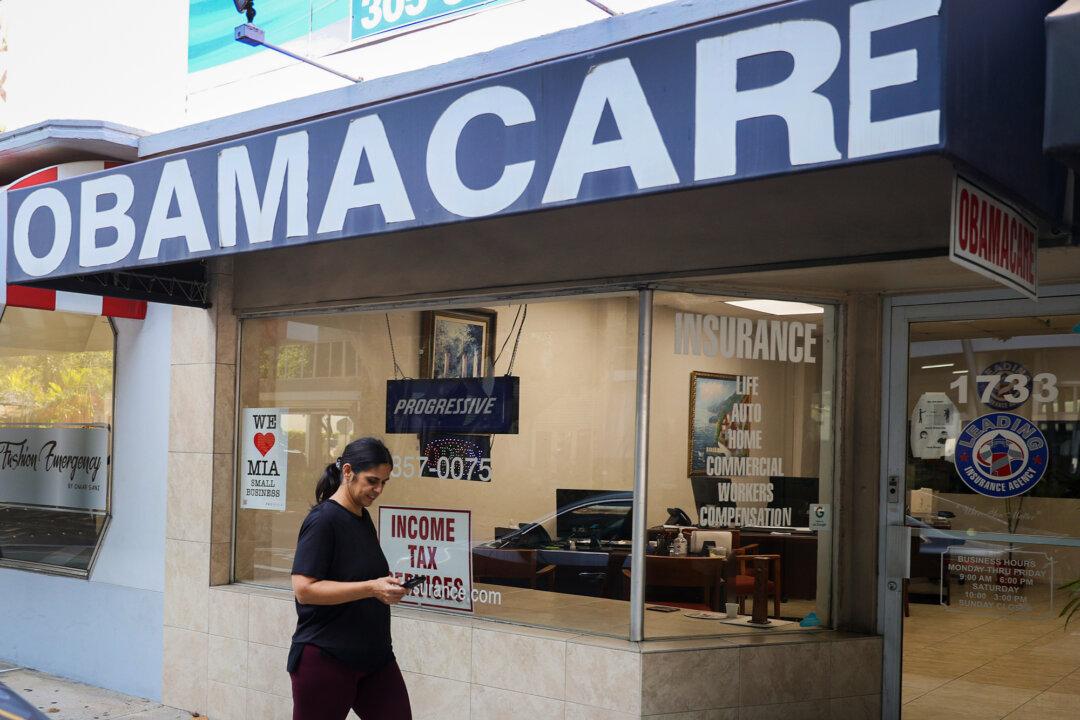 A pedestrian walks past an insurance agency that offers Affordable Care Act plans, in Miami on Jan. 28, 2021. Following the COVID-19 pandemic and enhanced subsidies approved by Congress in 2021, enrollment more than doubled, reaching a record 24.3 million in 2025. (Joe Raedle/Getty Images)