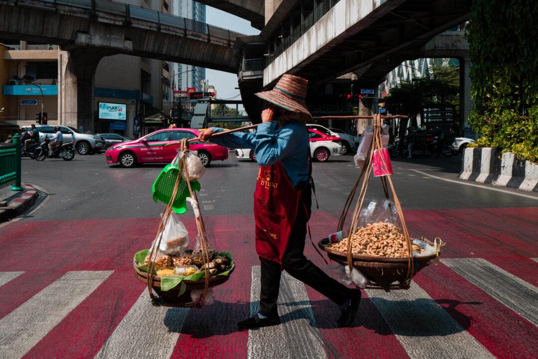 A monkey nut vendor crosses a road in Bangkok, on Feb. 9, 2026. (Anthony Wallace/AFP via Getty Images)