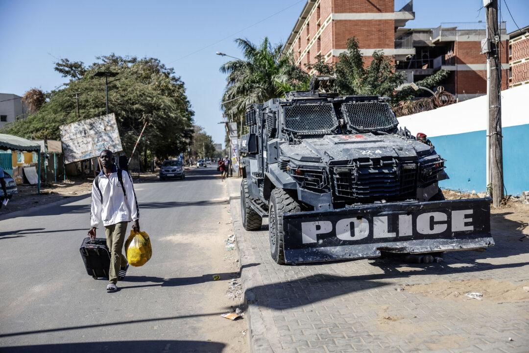 A student carrying his belongings passes a Senegalese police armored vehicle as he leaves the Cheikh Anta Diop University, on Feb. 10, 2026. A student died after clashes erupted between police and students protesting delays in grant payments at a Senegal university, the west African country's government said. (Patrick Meinhardt/AFP via Getty Images)