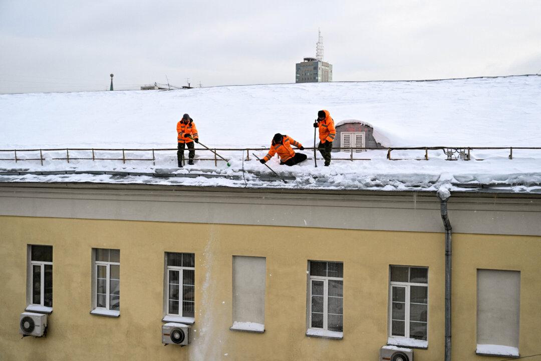 Workers remove ice from the roof of a building in central Moscow, on Feb. 10, 2026. (Hector Retamal/AFP via Getty Images)
