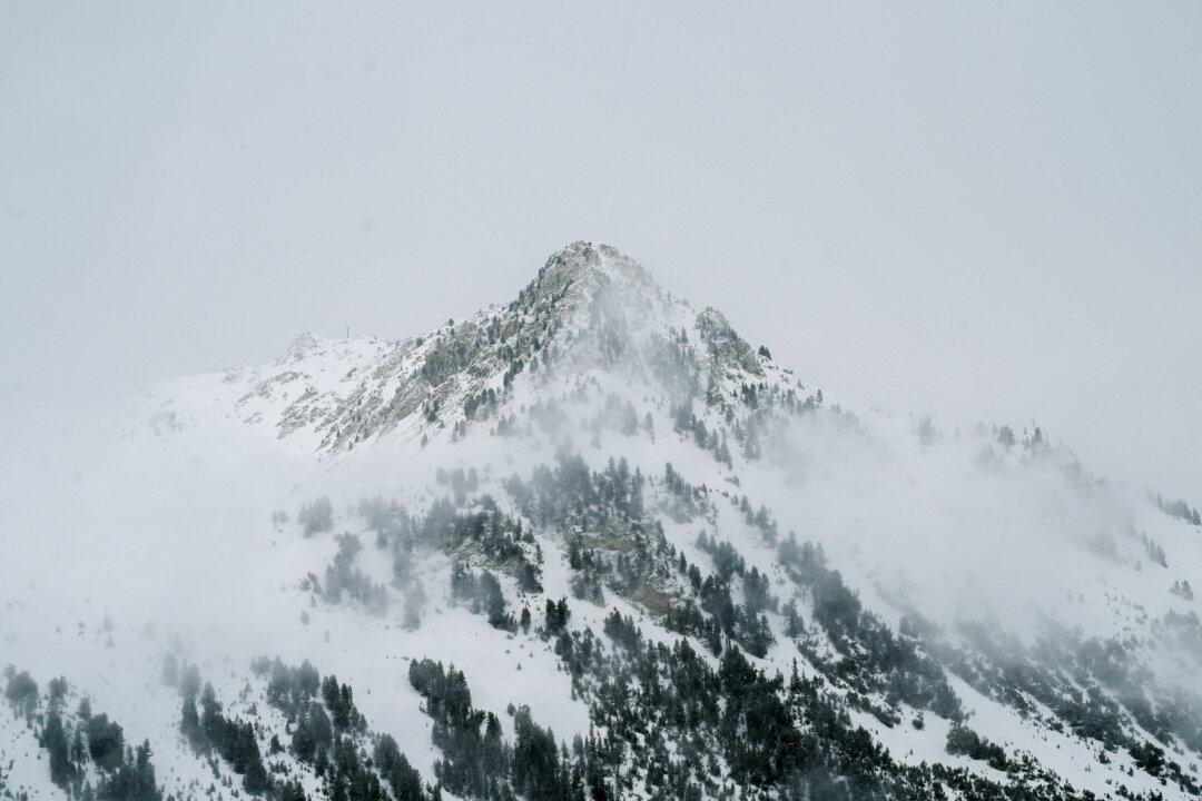 The summit of the snow-covered Aiguille Rouge mountain is shrouded in thick fog during heavy snowfall at the Arc 2000 ski resort in Bourg Saint Maurice in France, on Feb. 10 2026. (Matthieu Delaty/Hans Lucas/AFP via Getty Images)