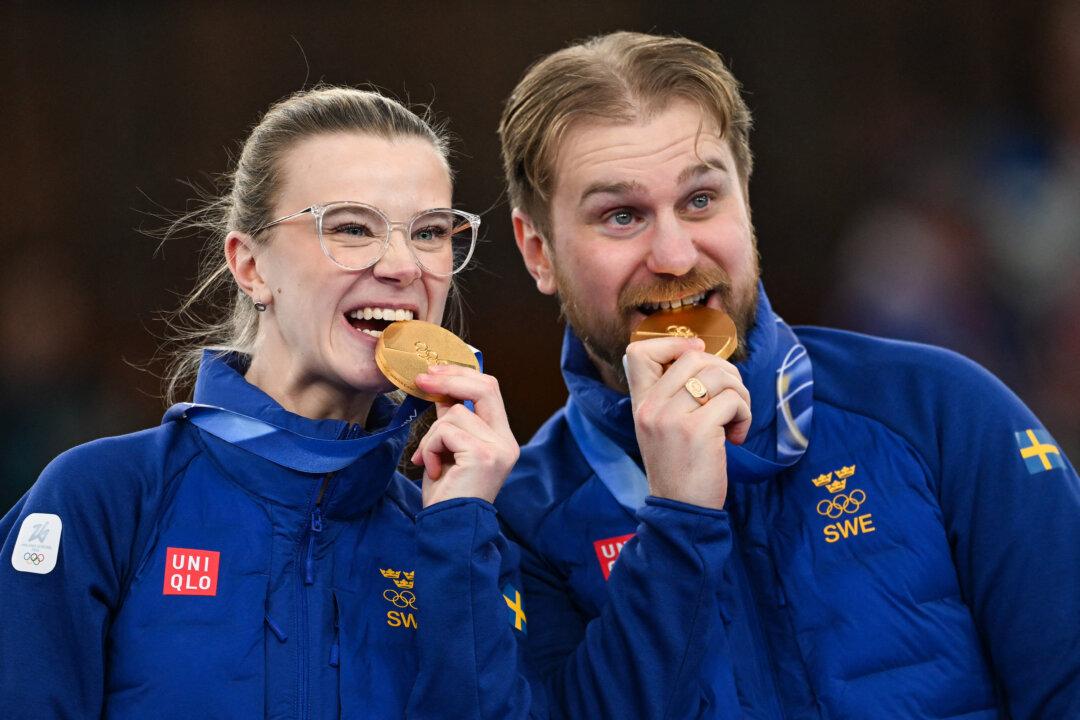 Sweden's gold medalists Isabella and Rasmus Wrana bite their medals on the podium of the curling mixed doubles event during the Milan Cortina 2026 Winter Olympic Games at the Cortina Curling Olympic Stadium in Cortina d'Ampezzo, Italy, on Feb. 10, 2026. (François-Xavier Marit/AFP via Getty Images)