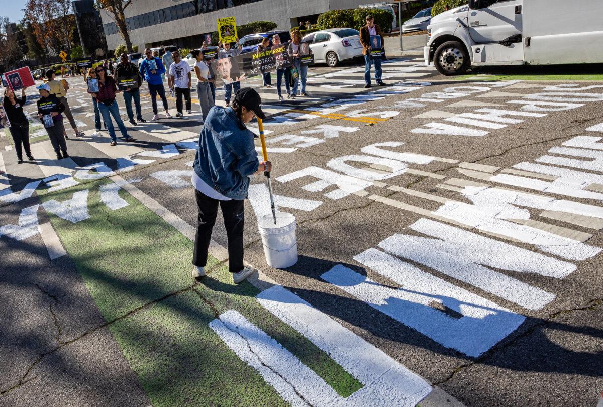 Parents who blame social media platform Snapchat for contributing to their loved one's death, paint the names of the deceased near the offices of Snap Inc., in Santa Monica, Calif., on Feb. 12, 2026. (John Fredricks/The Epoch Times)