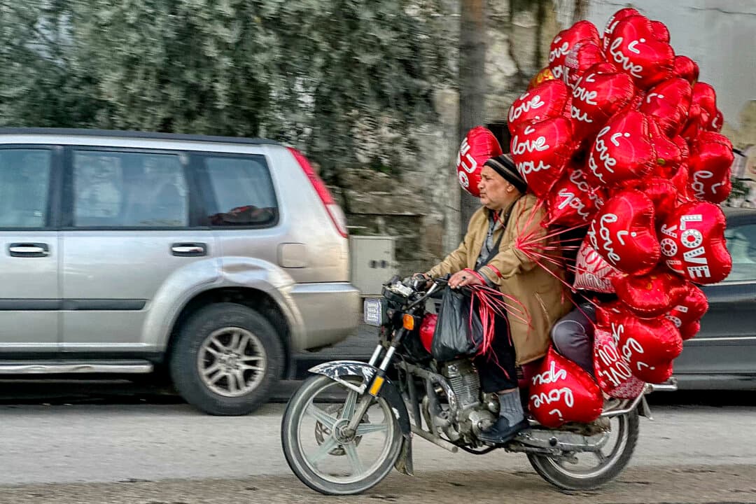 An ambulant vendor rides a motorcycle while transporting heart-shaped Valentine's balloons in Beirut, Lebanon, on Feb. 13, 2026. (Joseph Eid/AFP via Getty Images)