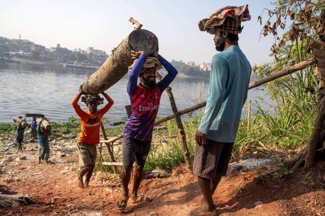 Bangladeshi workers carry logs near the Buriganga River in Kamrangirchar on the outskirts of Dhaka, on Feb. 14, 2026. (Mohd Rasfan/AFP via Getty Images)