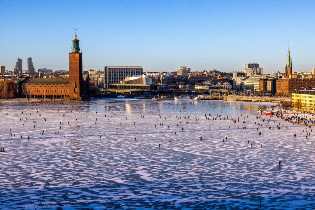 People walk and skate on the ice at Riddarfjarden, in front of the city hall in central Stockholm, Sweden, on a sunny Feb. 14, 2026. (Par Backstrom/TT News Agency/AFP via Getty Images)